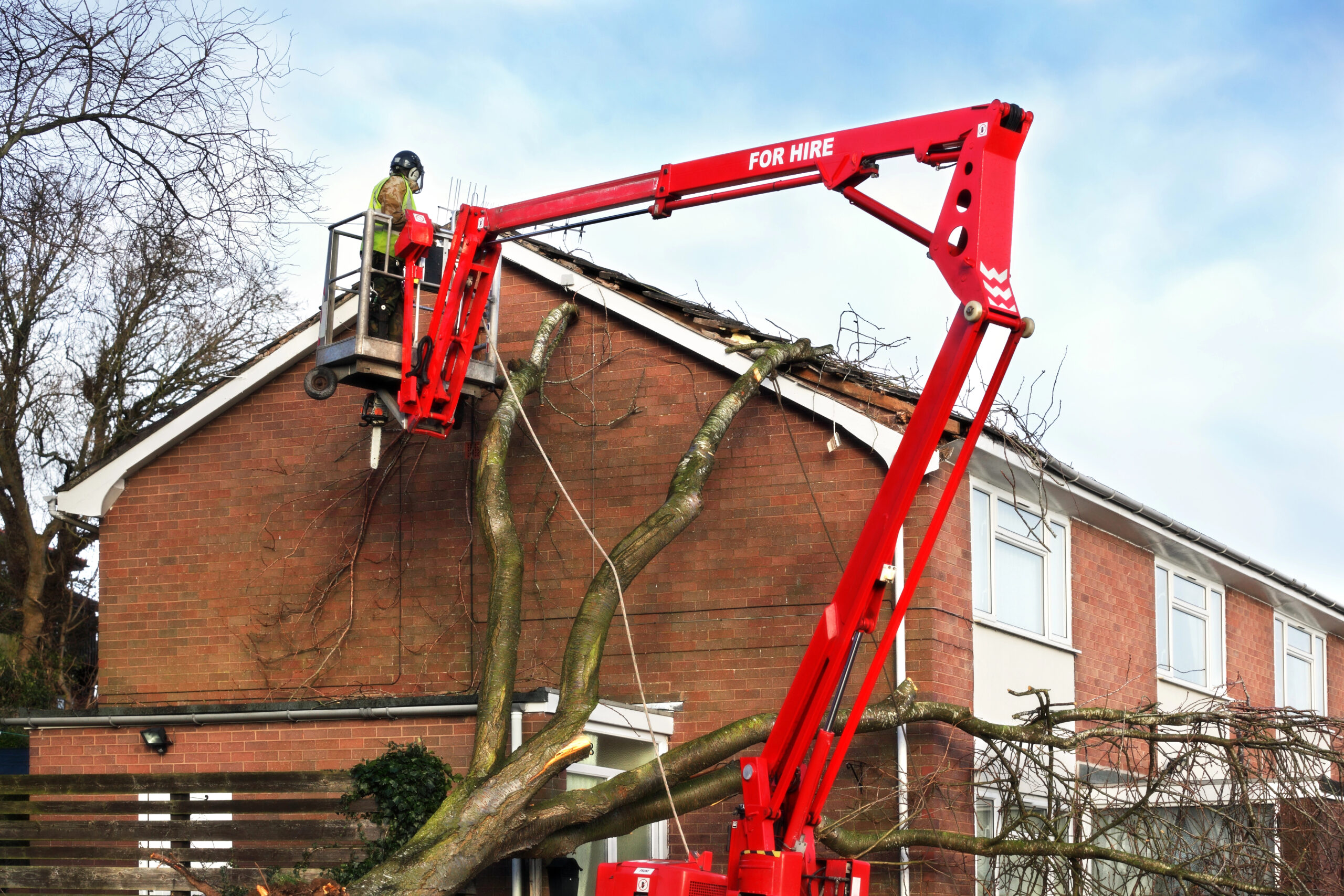 Worker on crane cleaning and restoring property that's been damaged in a storm